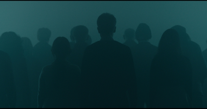 Silhouetted crowd standing in blue-green fog in Waiting for the End